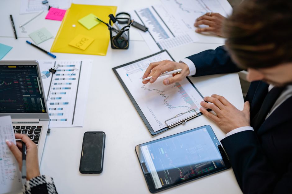 Tim pregledava financijske grafikone i digitalne podatke na tabletima u uredu